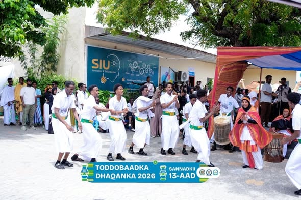 Male students in white traditional dress perform a cultural dance outside the SIU Innovation and Skills Center during Cultural Week.