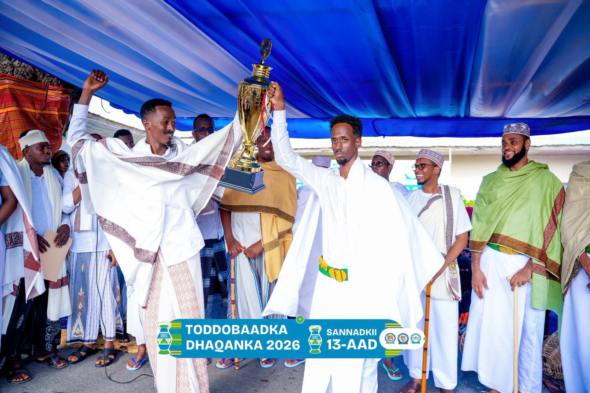 Students in traditional dress raise a trophy together in celebration during the Cultural Week awards presentation.