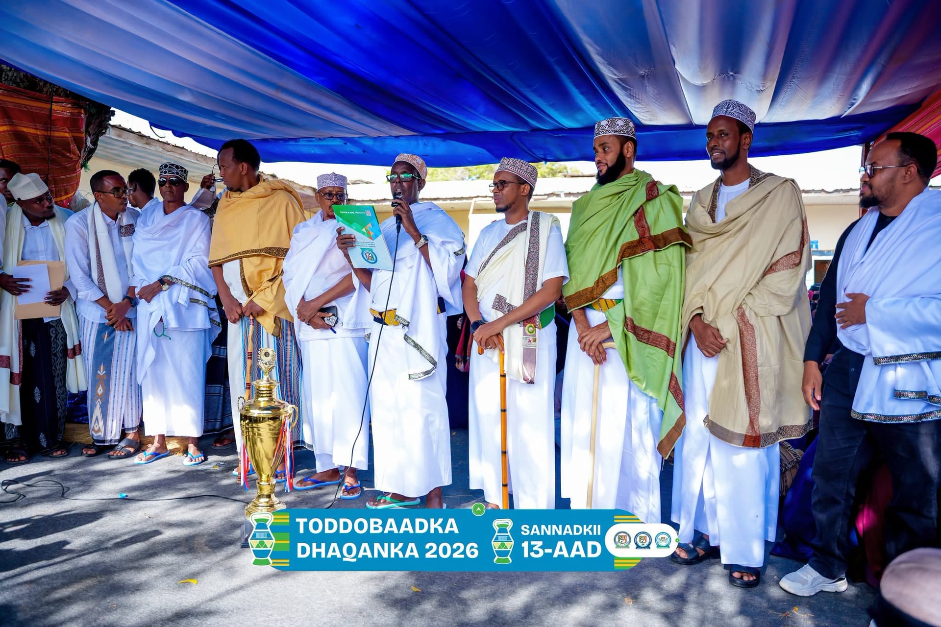 University representatives in traditional dress gather around a trophy during the Cultural Week awards ceremony.